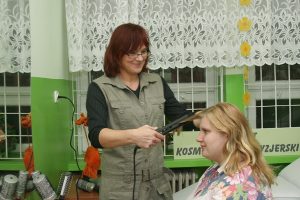 fryzjerka prostuje włosy uczennicy