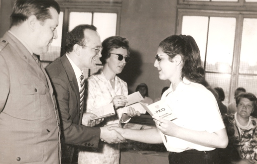 uczennica odbiera książeczkę PKO od dyrektora